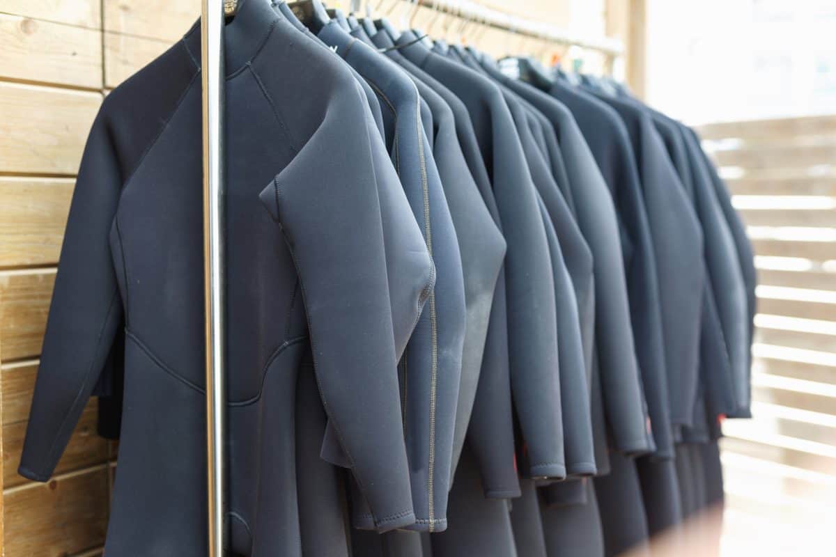 Black fashionable surfing wetsuits hanging on rack for rent in surf club