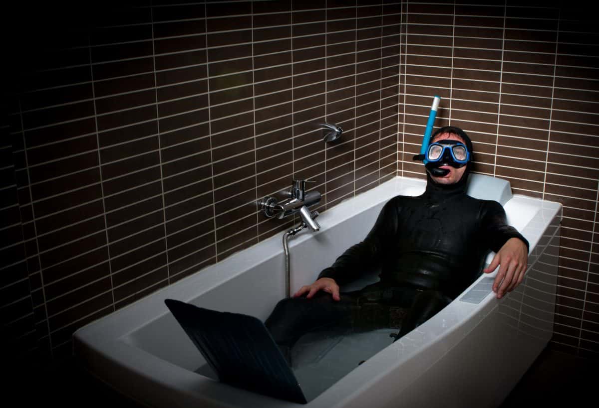 man in neoprene dive suit in bath