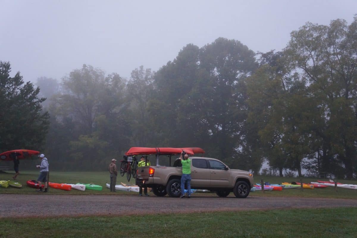 2 men loading a red kayak onto a grey truck