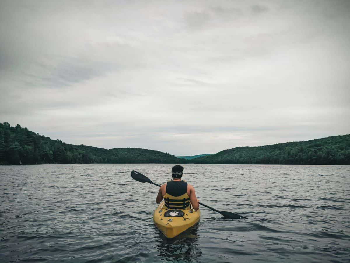 Man in Sit in kayak facing outward towards lake