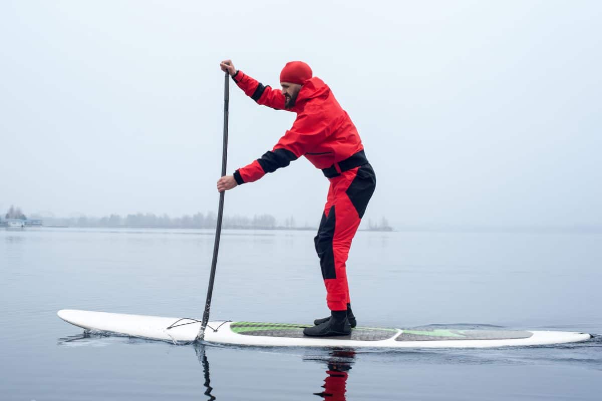 Athletic man stand up paddle board - winter paddling