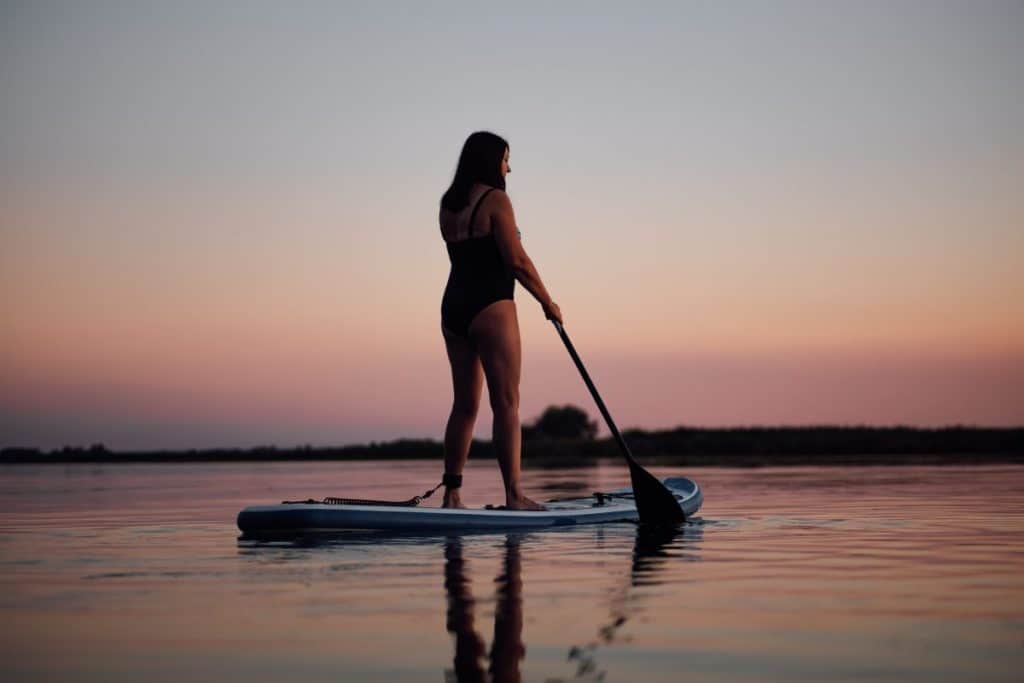 Back side of middle aged woman sup boarding