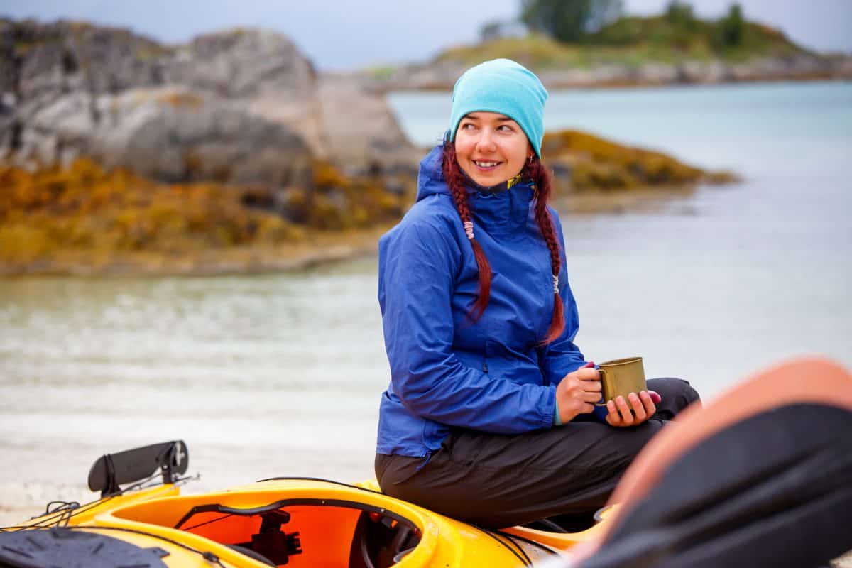 Brunette tourist with cup sitting on sit inside kayak