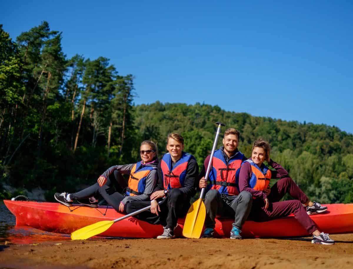 Group of people wearing life jackets near kayak