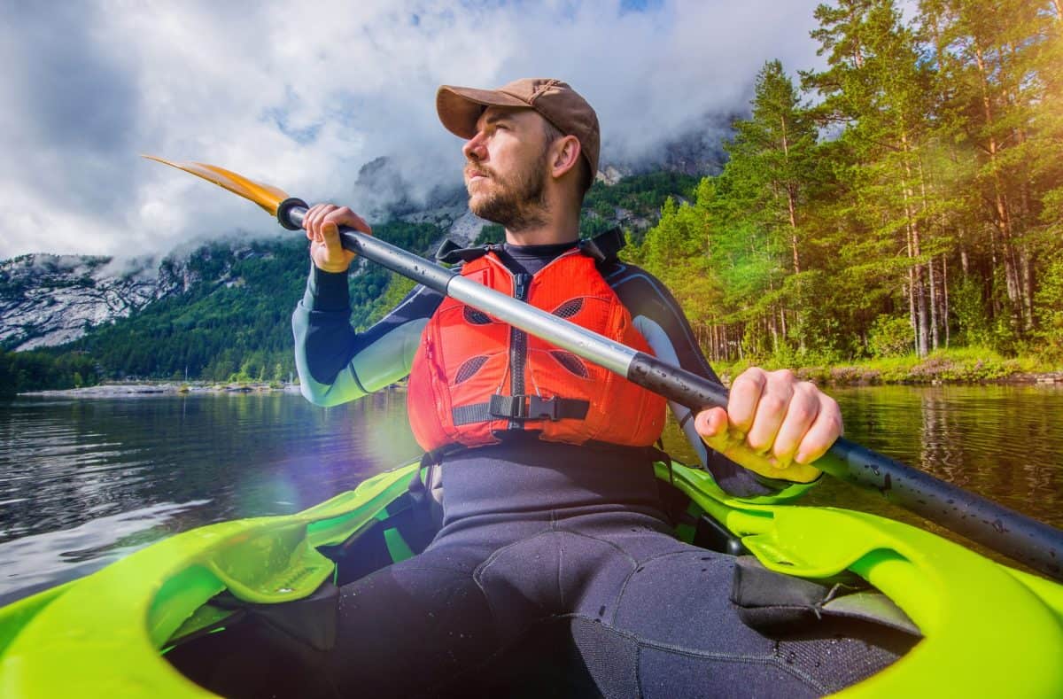 Man paddling kayak wearing full wetsuit vs drysuitsuit
