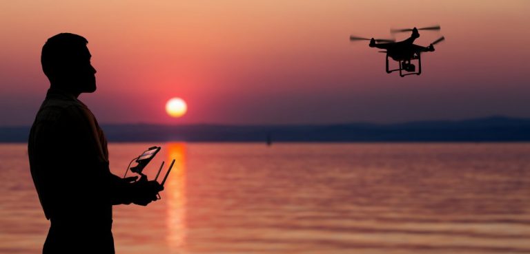 Man flying a fishing drone near seaside at the sunset