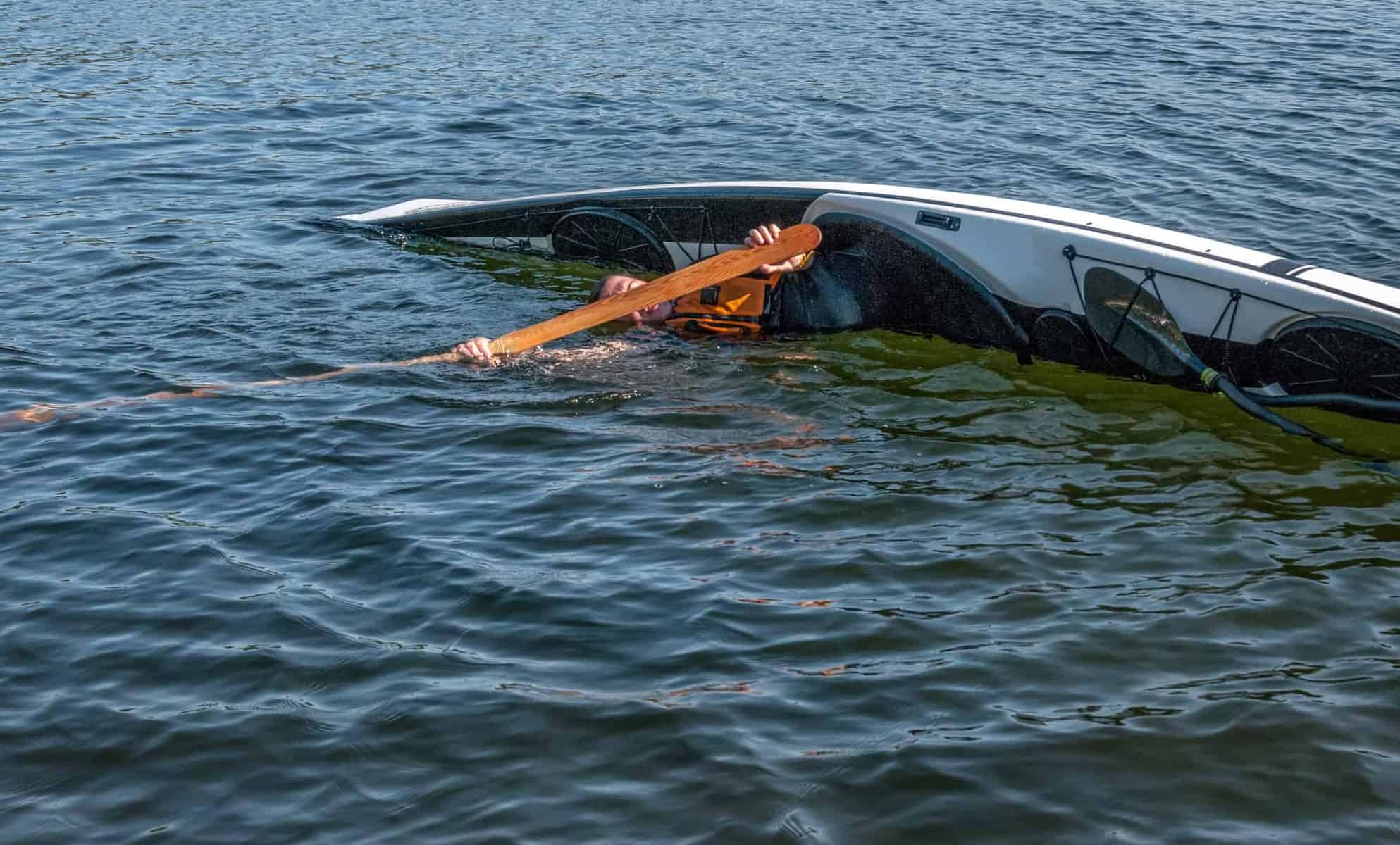 man rolling with a kayak on a lake 