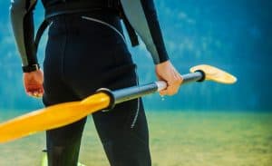Man In wetsuit holding kayak paddle
