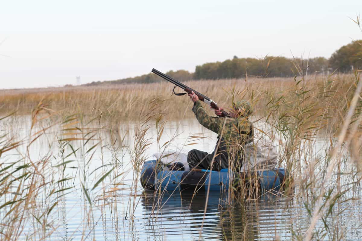 Hunter in an inflatable kayak shoots duck