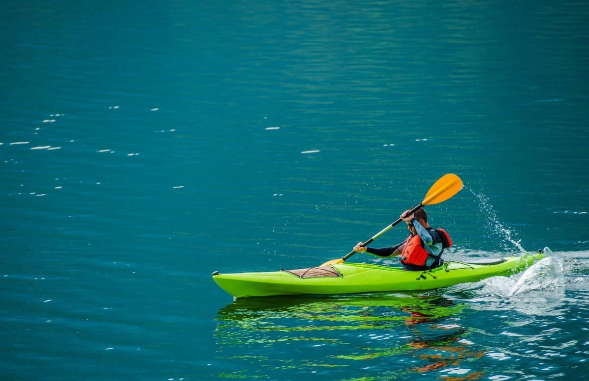 Man in green transitional touring kayak on open water
