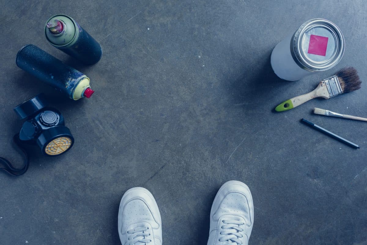 DIY painting of kayak guide - view looking down of a pair of feet, spray can and paint