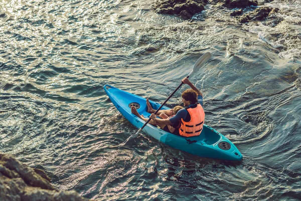 Man paddles a blue sit-on-top kayak in sea