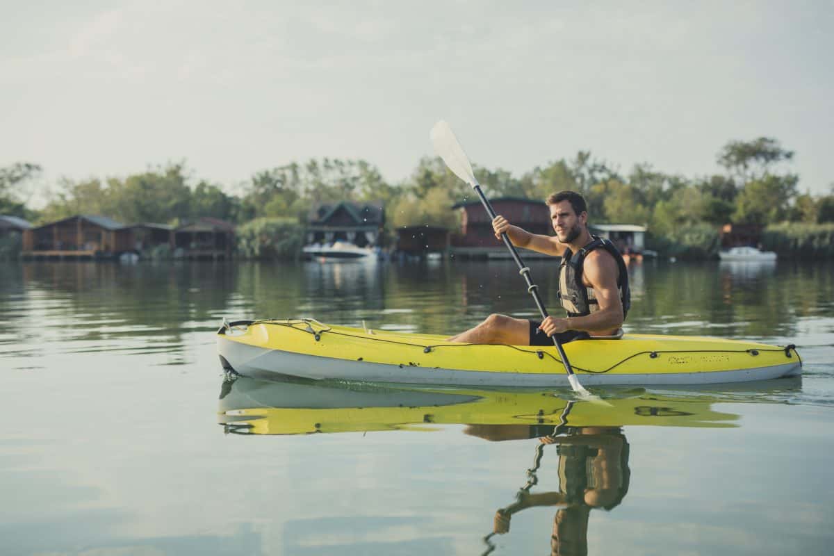 Handsome Caucasian man kayaker paddling on the river.