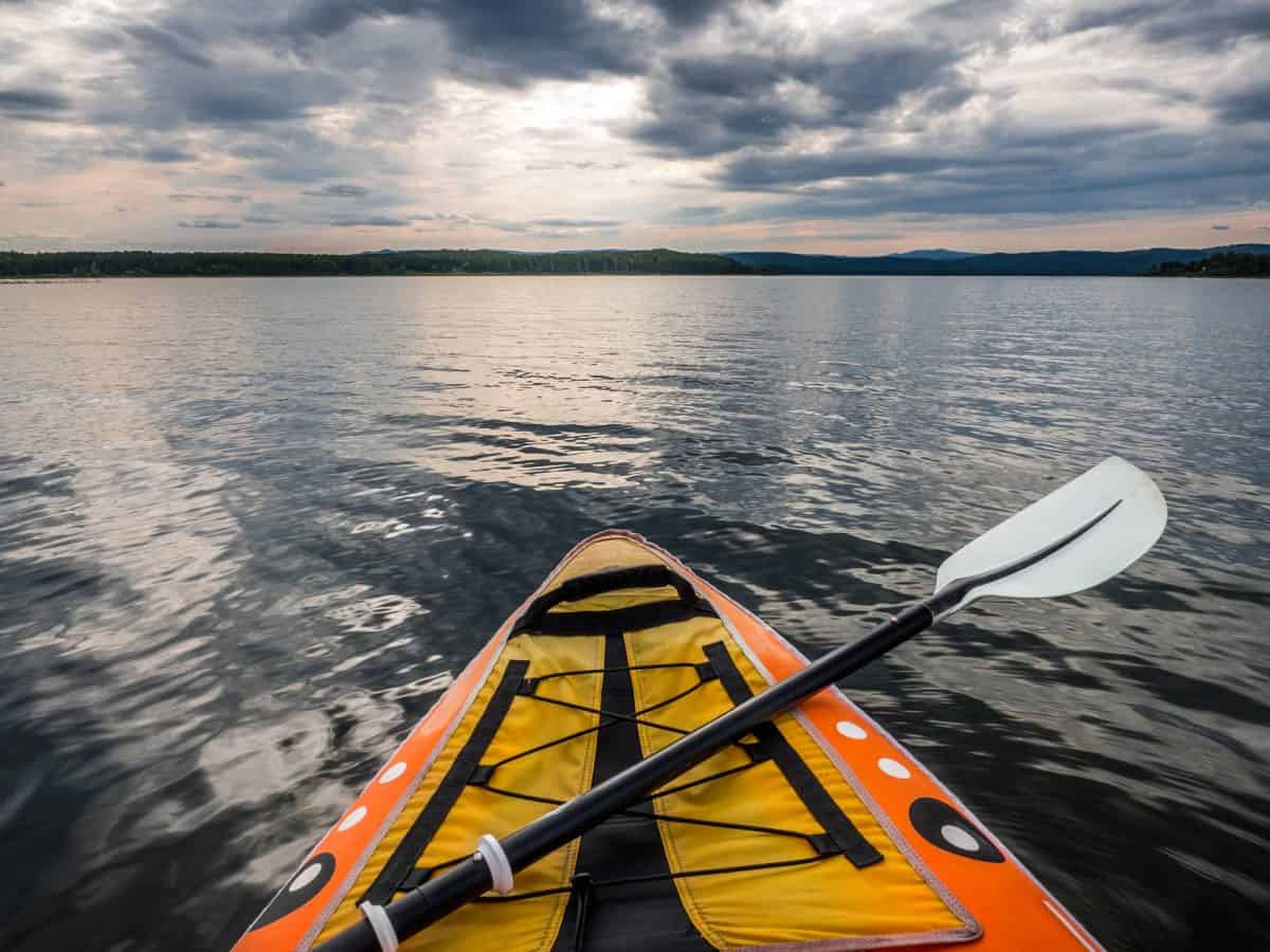 Point of view shot from inside kayak with paddle laying on deck on lake