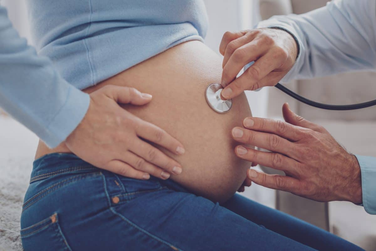 Kayaking While Pregnant - Big bump. Professional medical worker using stethoscope while doing health checkup