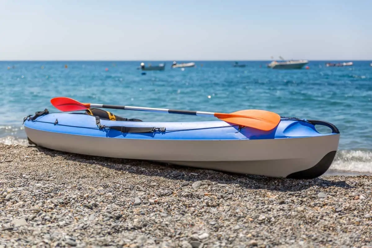 Mixed hard shell and inflatable kayak on rocky beach 