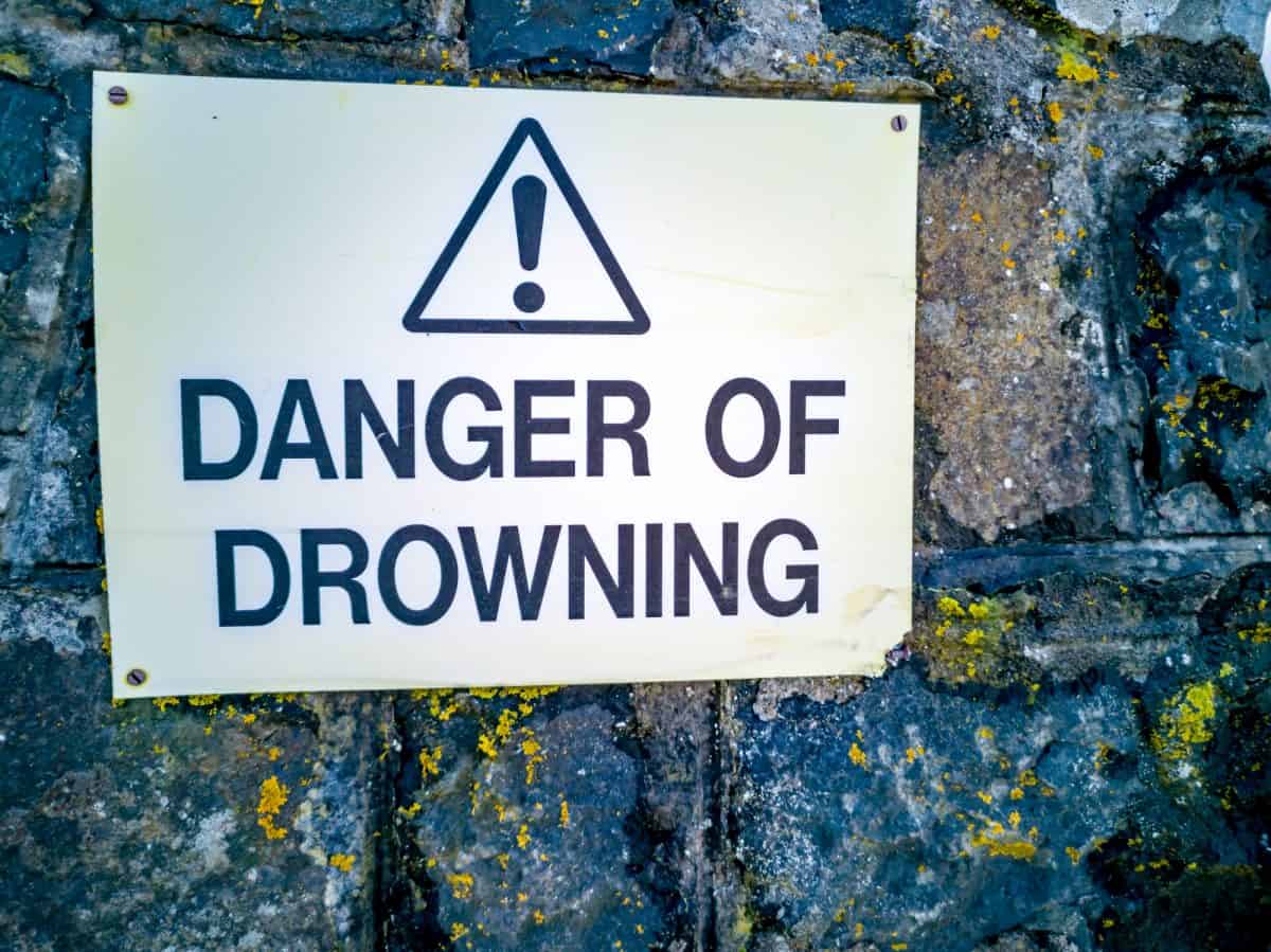 Low-Dam - Warning sign danger of drowning on a stone wall