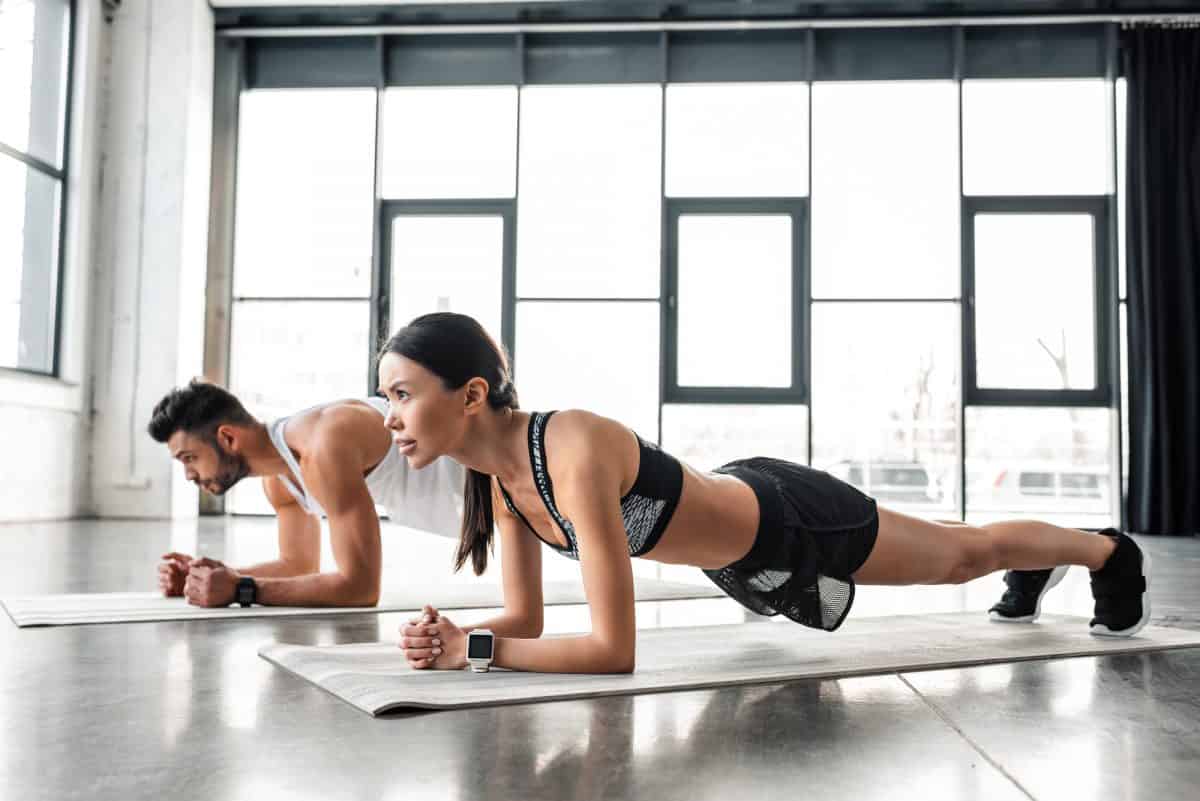 Couple in fitness gear performing plank exercise 