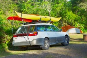 One red, one yellow kayak on the roof of a car