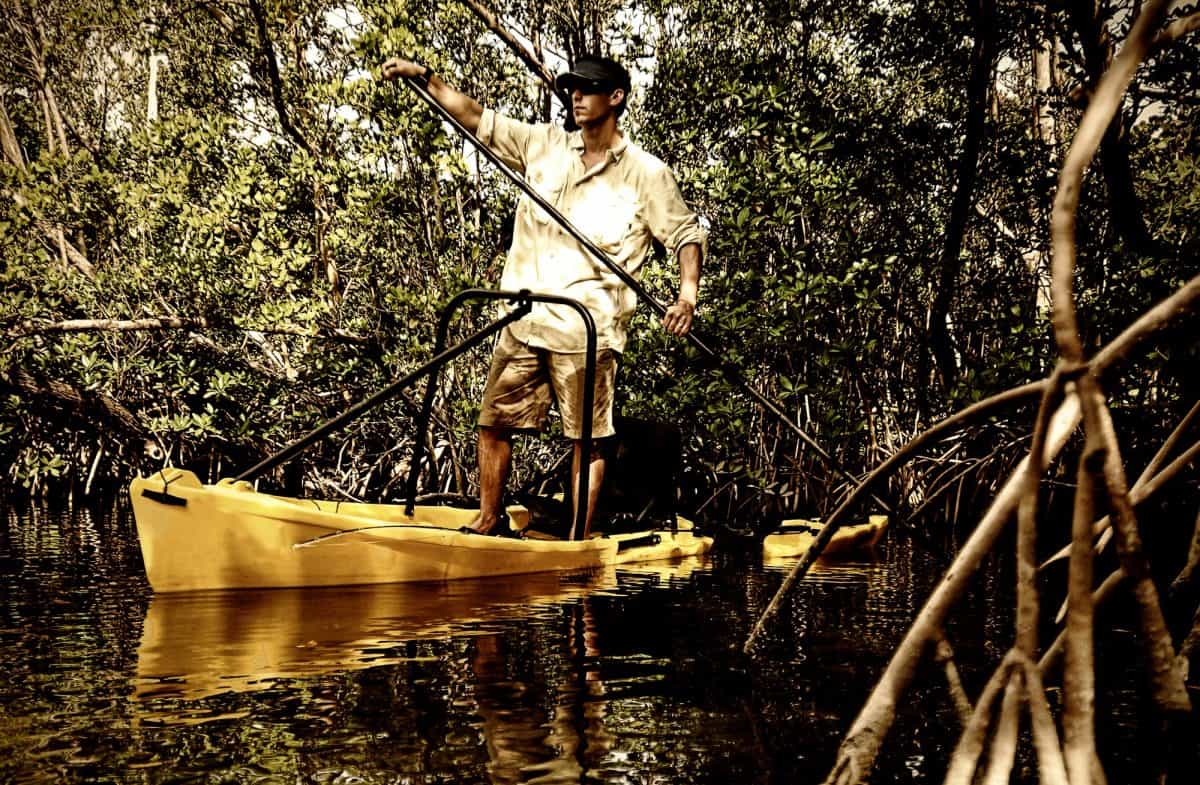 Man paddling down river in yellow fishingkayak for a fishing excursion