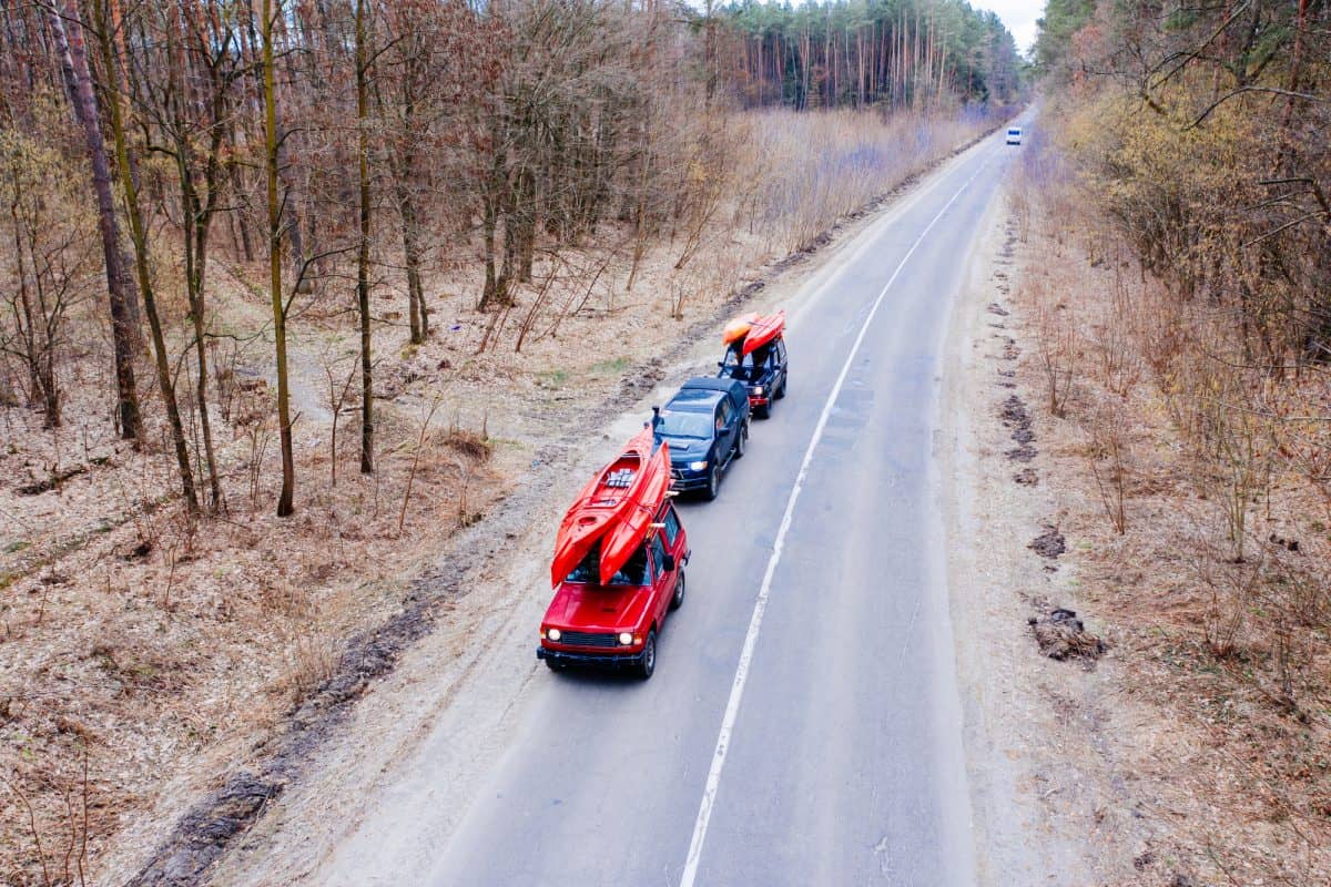 convoy of three cars carrying kayaks on their roofs