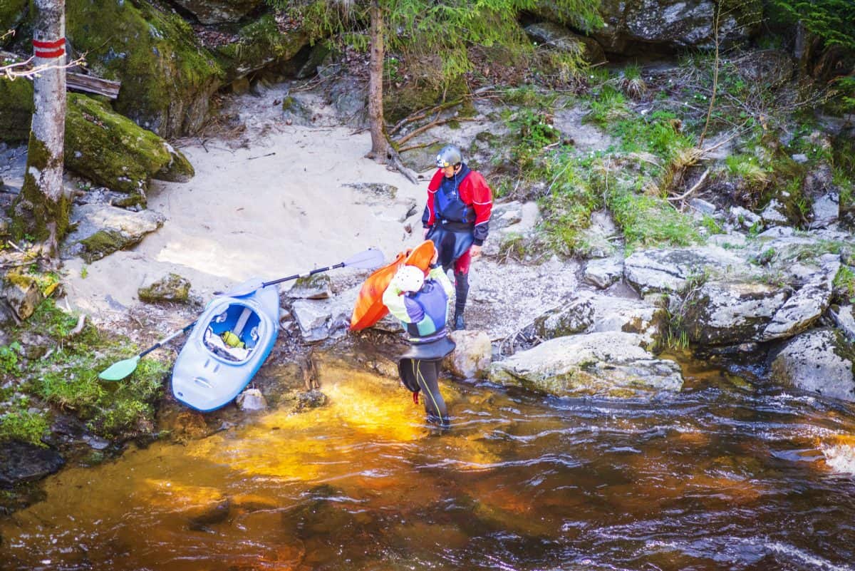 2 Kayakers Portaging A Kayak as the river bank