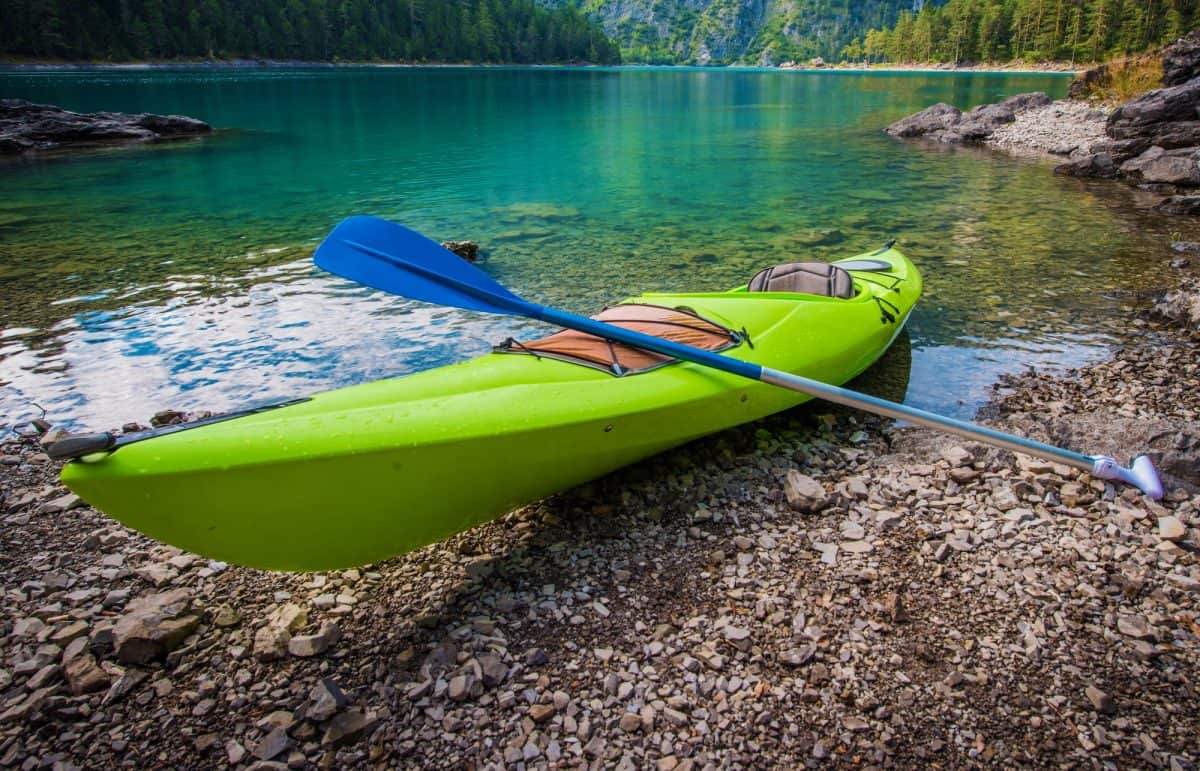 green hardshell kayaks on river bank