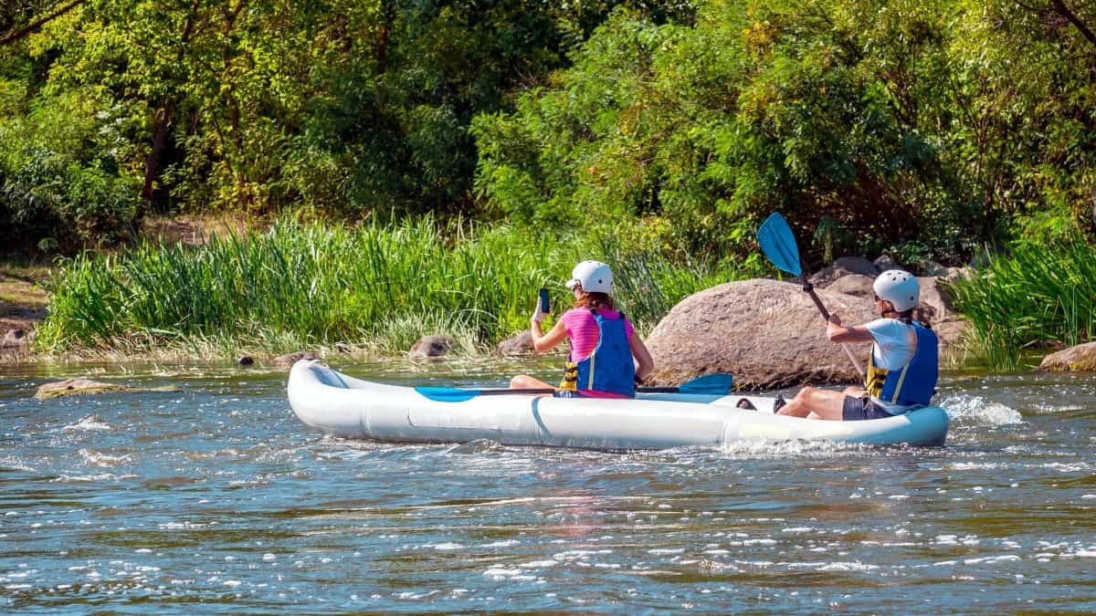 Two girls in a large inflatable kayak on the river.