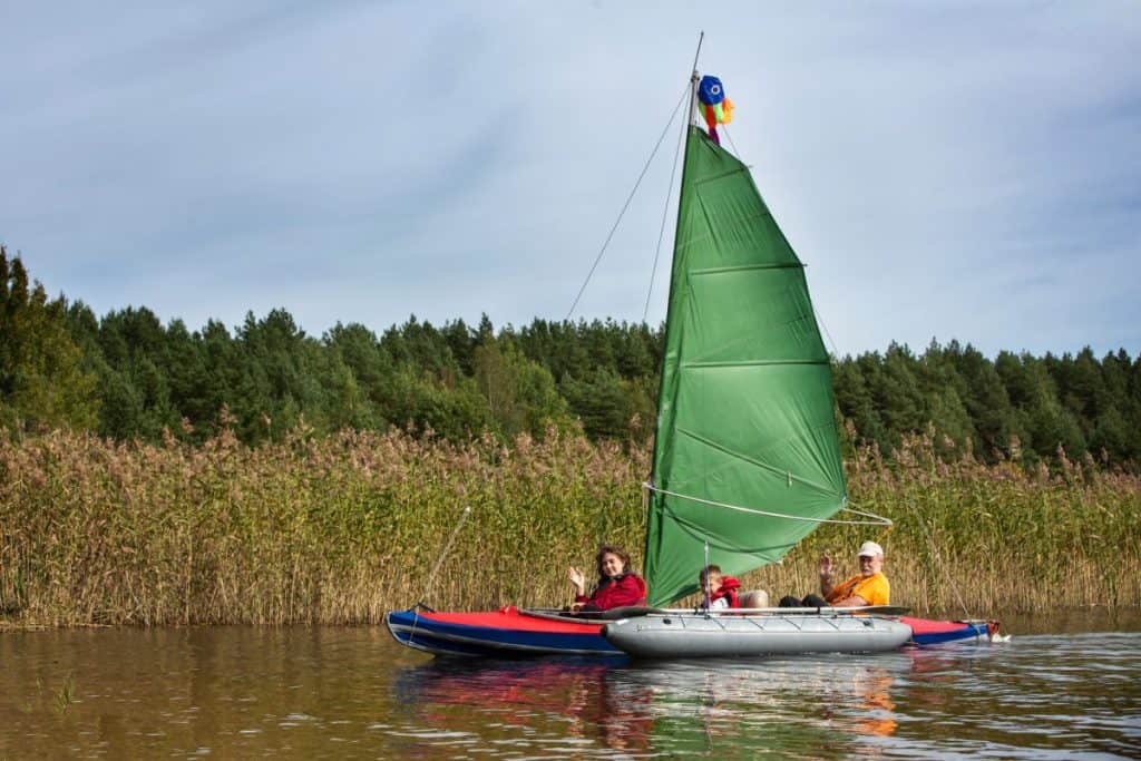 People travel by kayak with a sail.