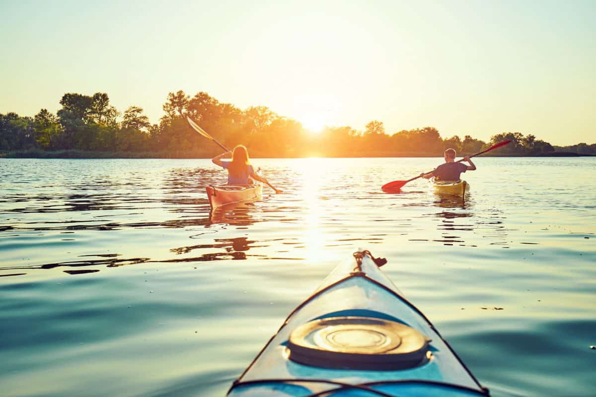 group paddling at sunset in recreational kayak for lakes