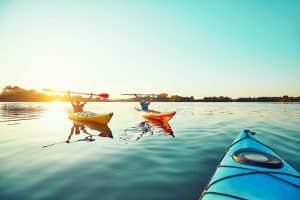 three kayak on the water at sunset
