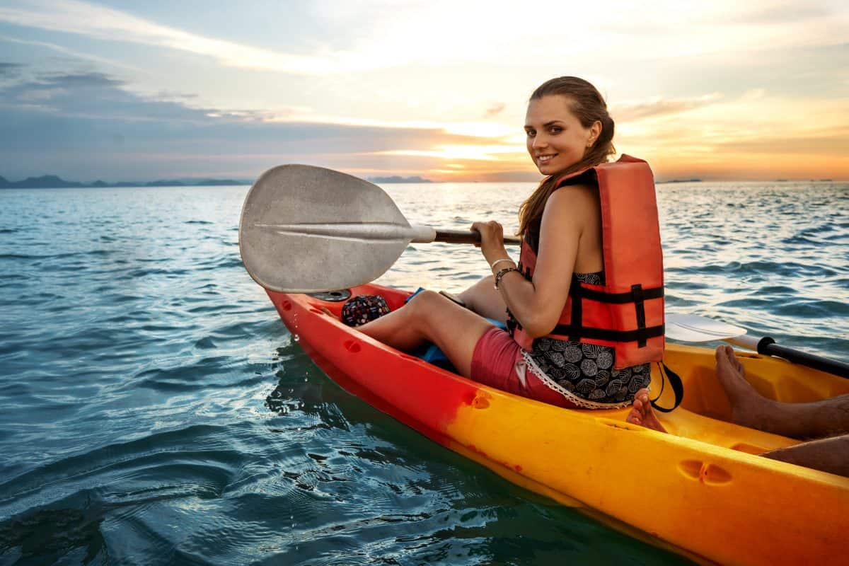 Kayak While Pregnant -  Couple kayaking together. Beautiful young couple kayaking on lake together and smiling at sunset