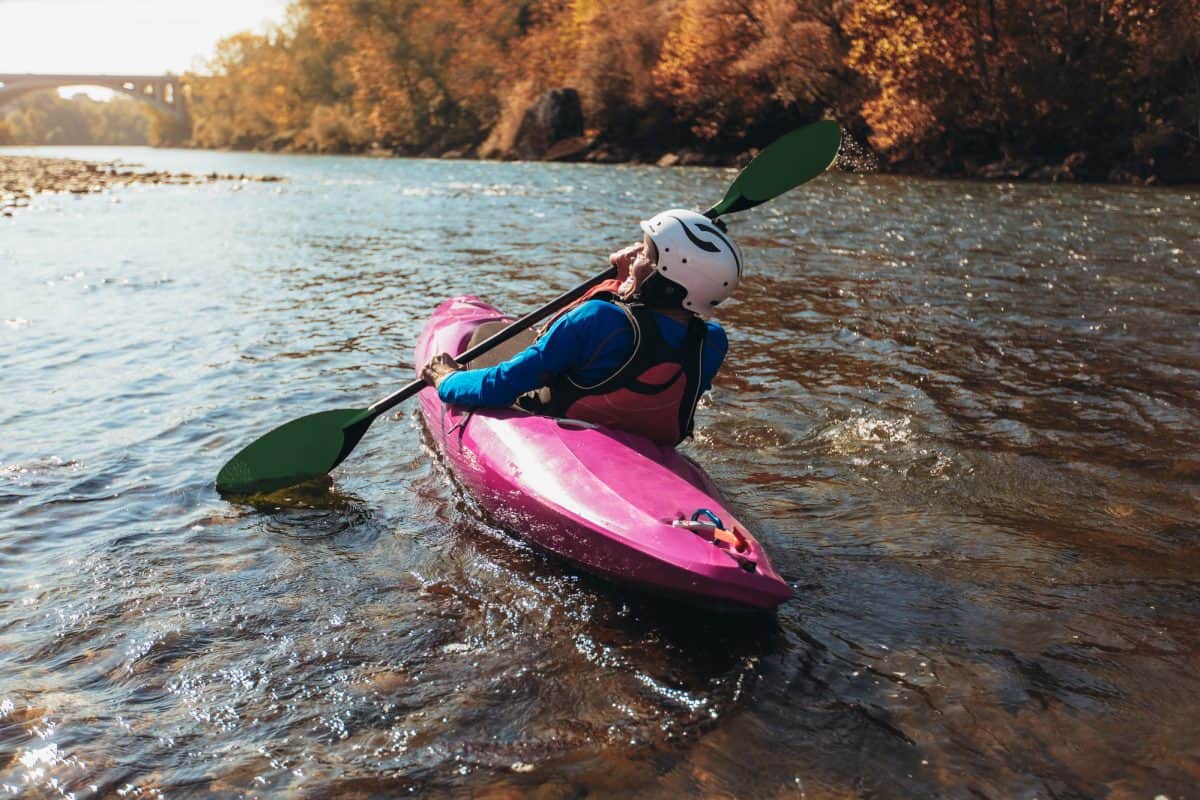 women in white helmet upstream kayaking in pink river boat 