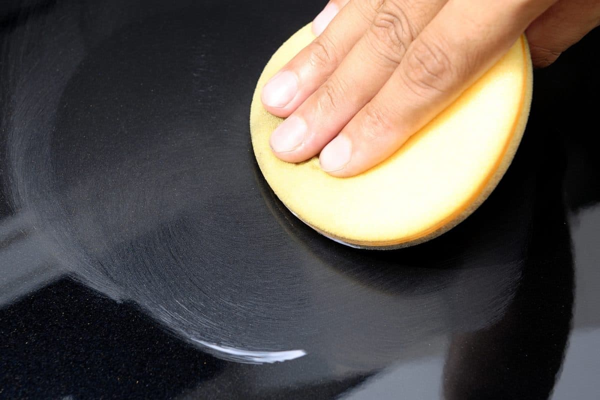 Hand applying polish on black kayak