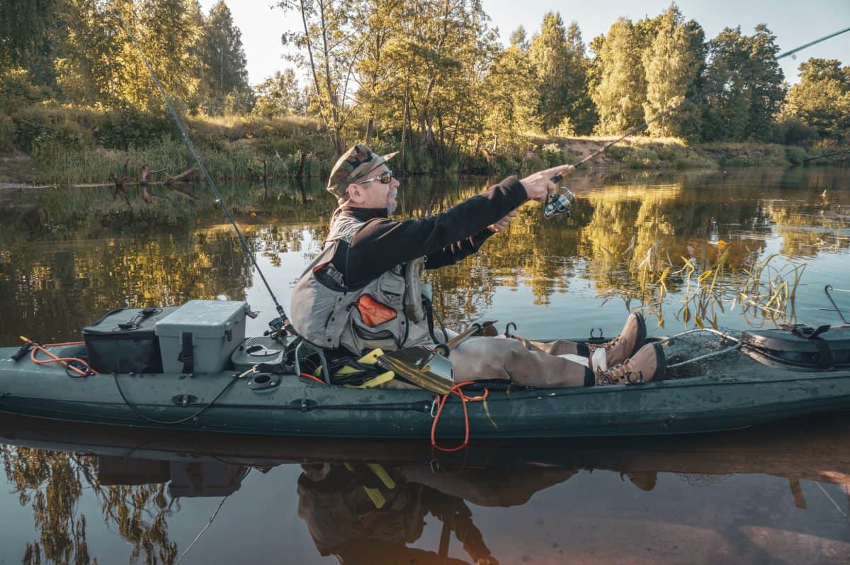Kayak Fisherman in kayak with rod, fishing crate 
