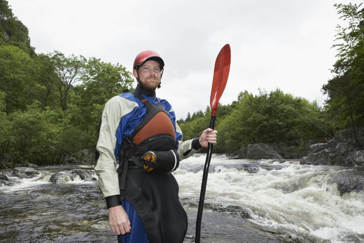 Man in dry suit demonstrating whitewater kayaking gear