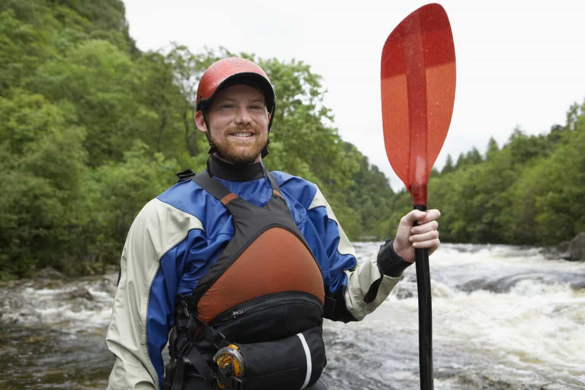 man holding paddle wearing blue and white kayak dry suit