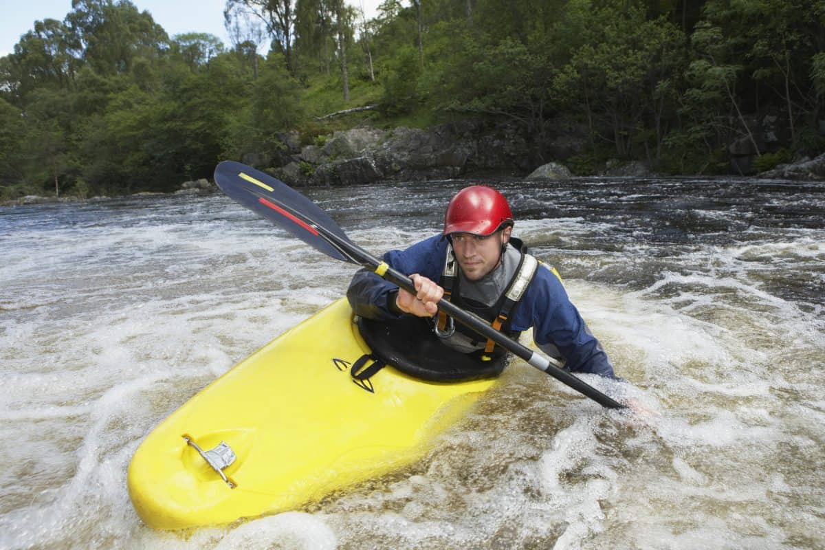 man edges whitewater kayak through rapids
