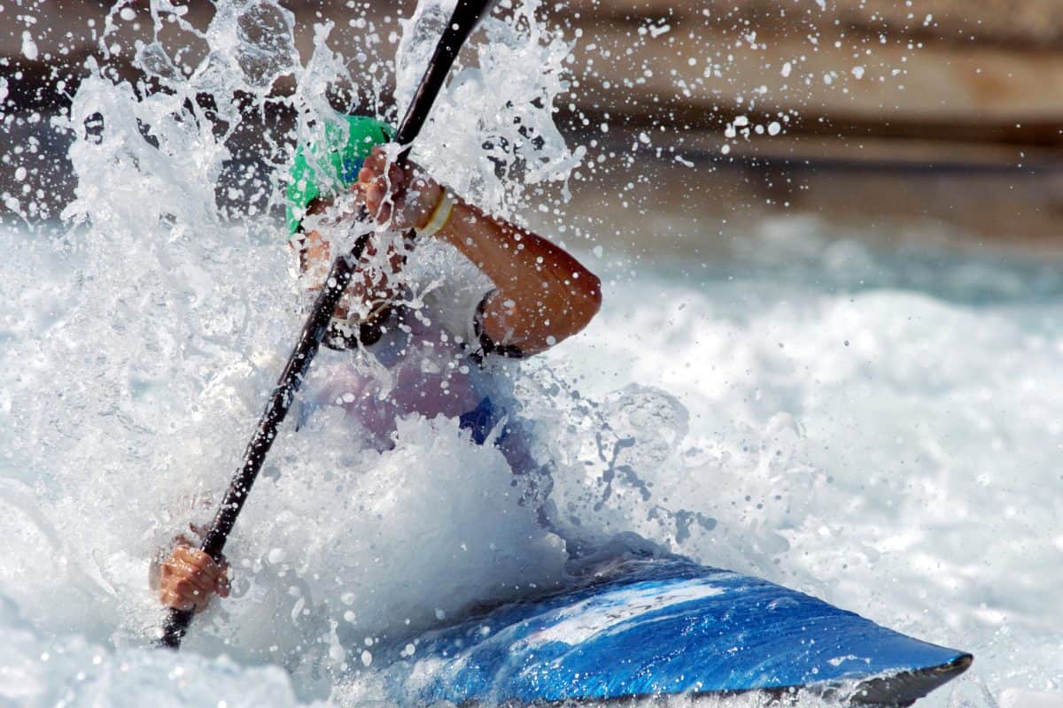 A kayaker races down the whitewater of a river using high angle paddle