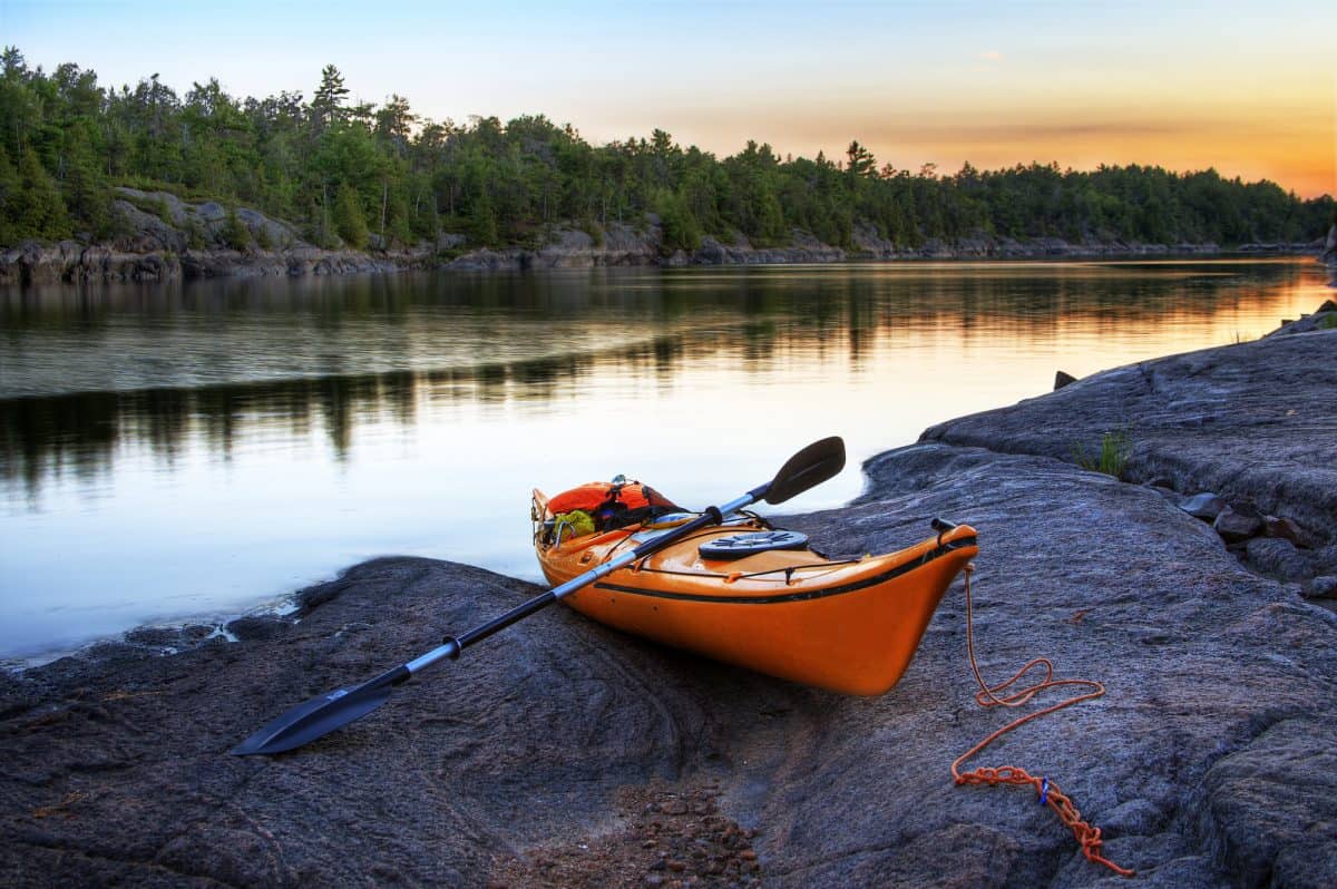 Affordable Kayak on River Bank, kayak's hull resting on rocks