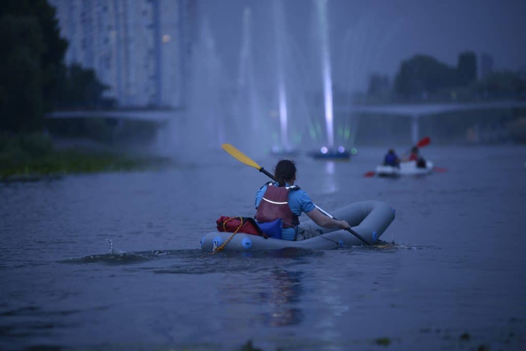 Kayak lights for kayaking at night - Man rowing kayak in the rain falling, evening light