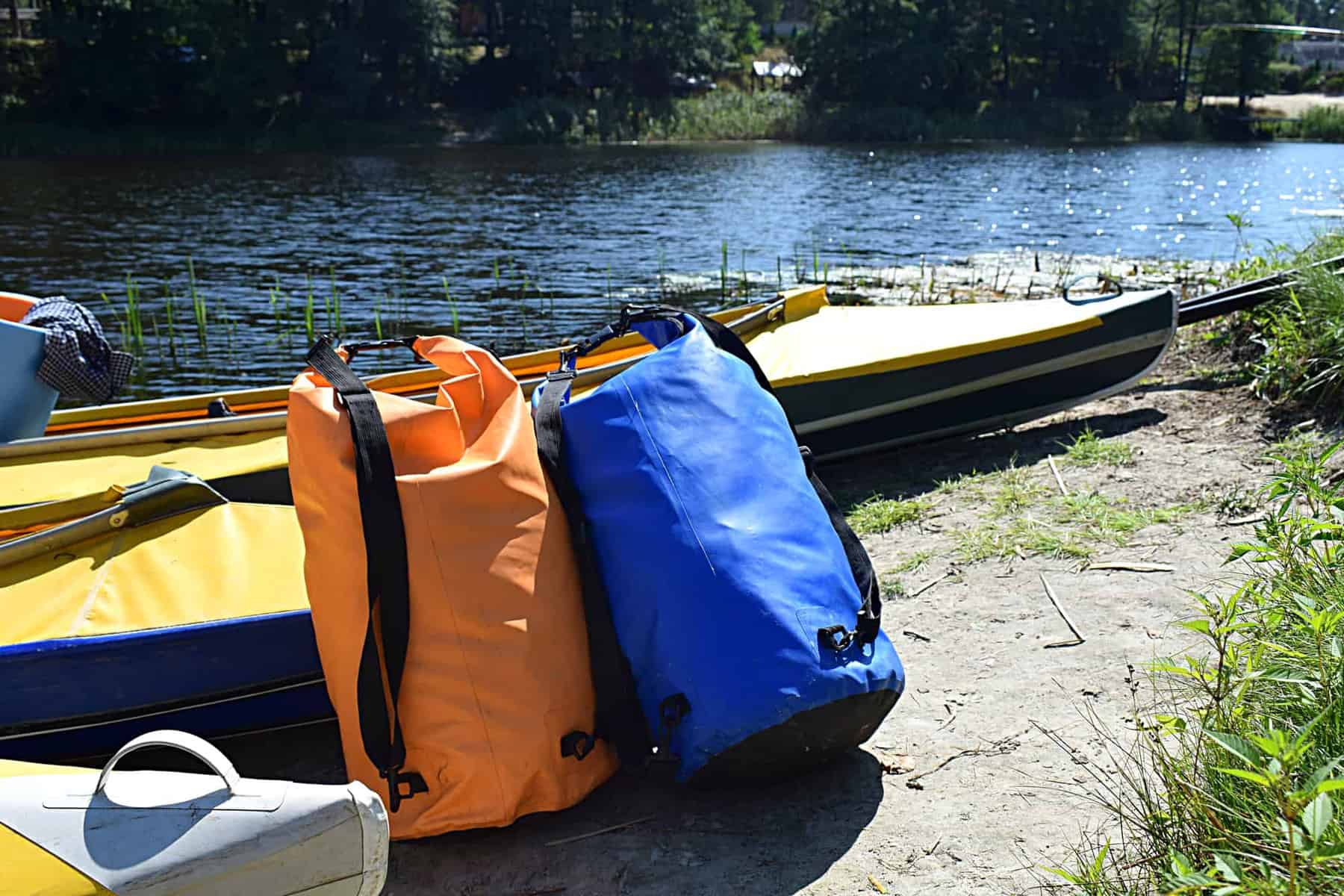 Kayaks and airtight gear bags on the beach while parking.
