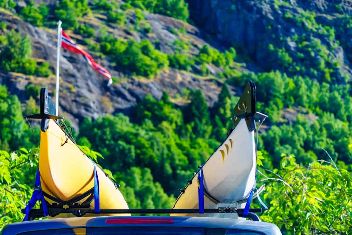 ar with two canoes on top roof in green norwegian mountains.