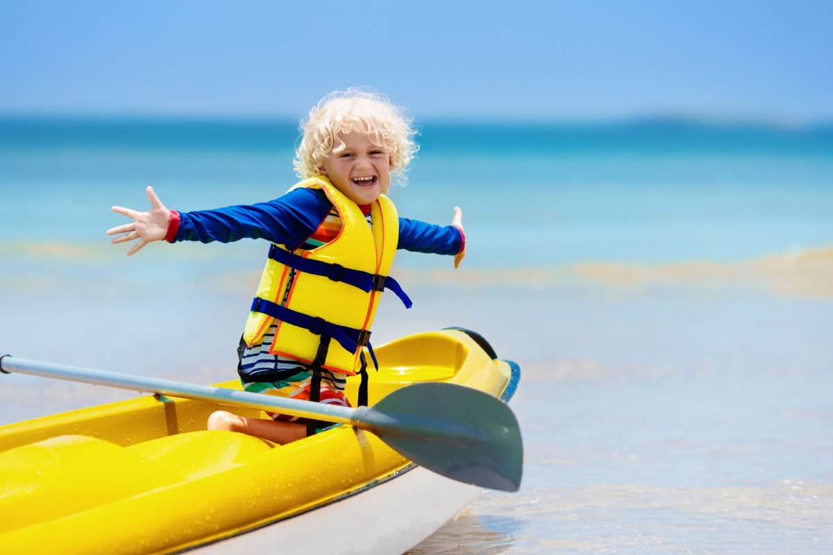 Kids kayaking in ocean. Children in kayak in tropical sea. Active vacation with young kid. Little boy in canoe on beautiful beach. Holiday activity with preschool child. Family water fun.