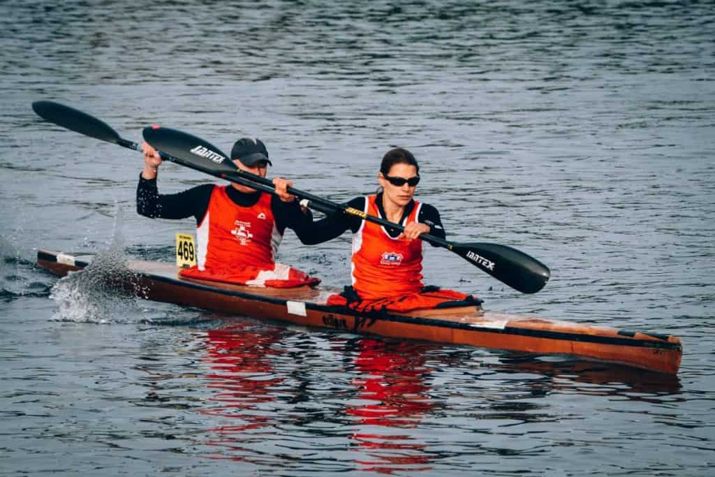 Male Female Couple paddling red and black racing kayak
