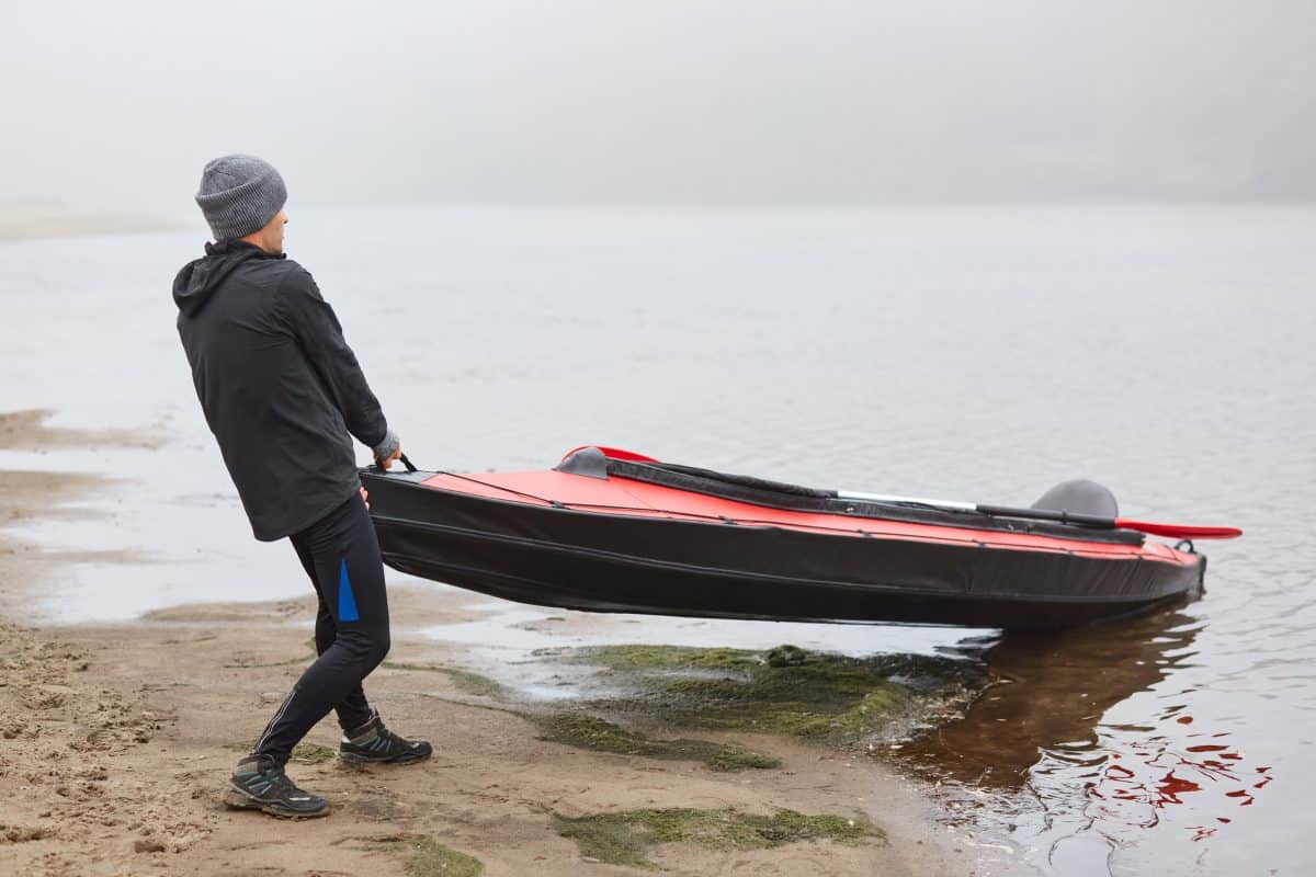 man getting out of a kayak on riverbank