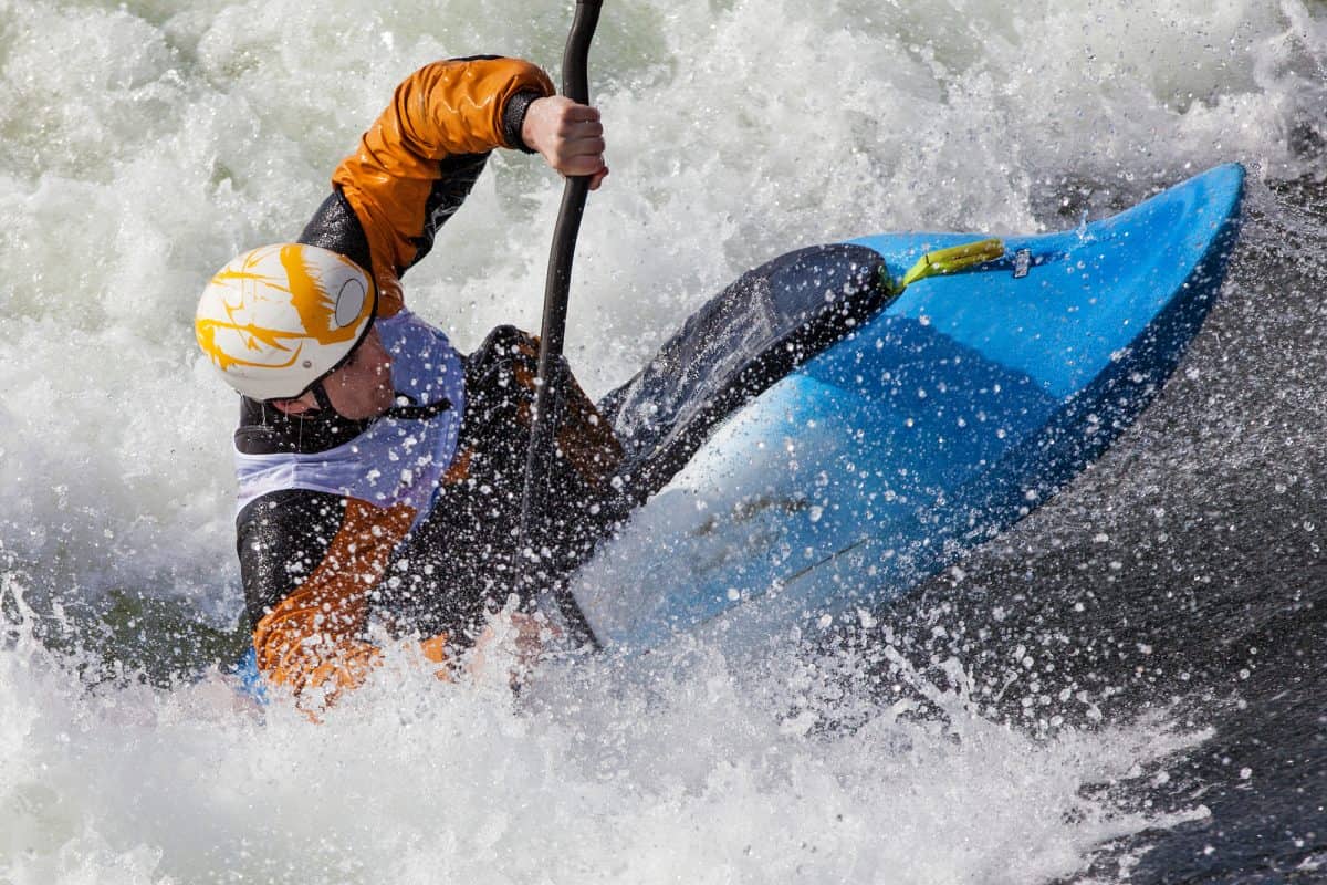 Man in blue whitewater kayak and Orange drysuit