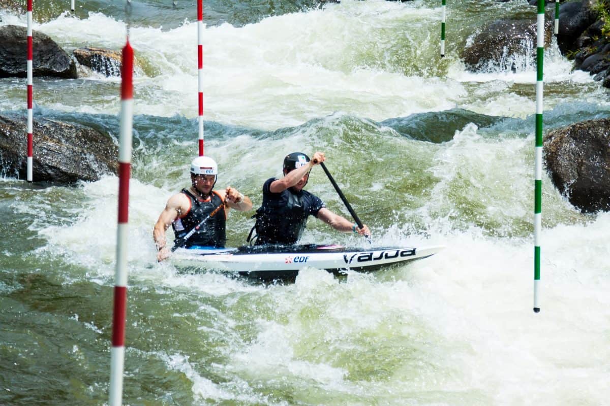 Two men in tandem sit on top kayak in rapid white water