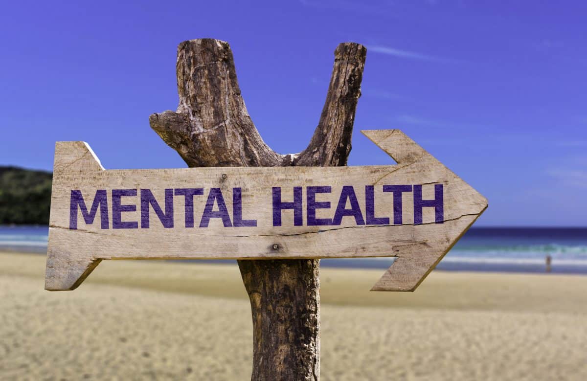 A sign saying mental health this way on beach