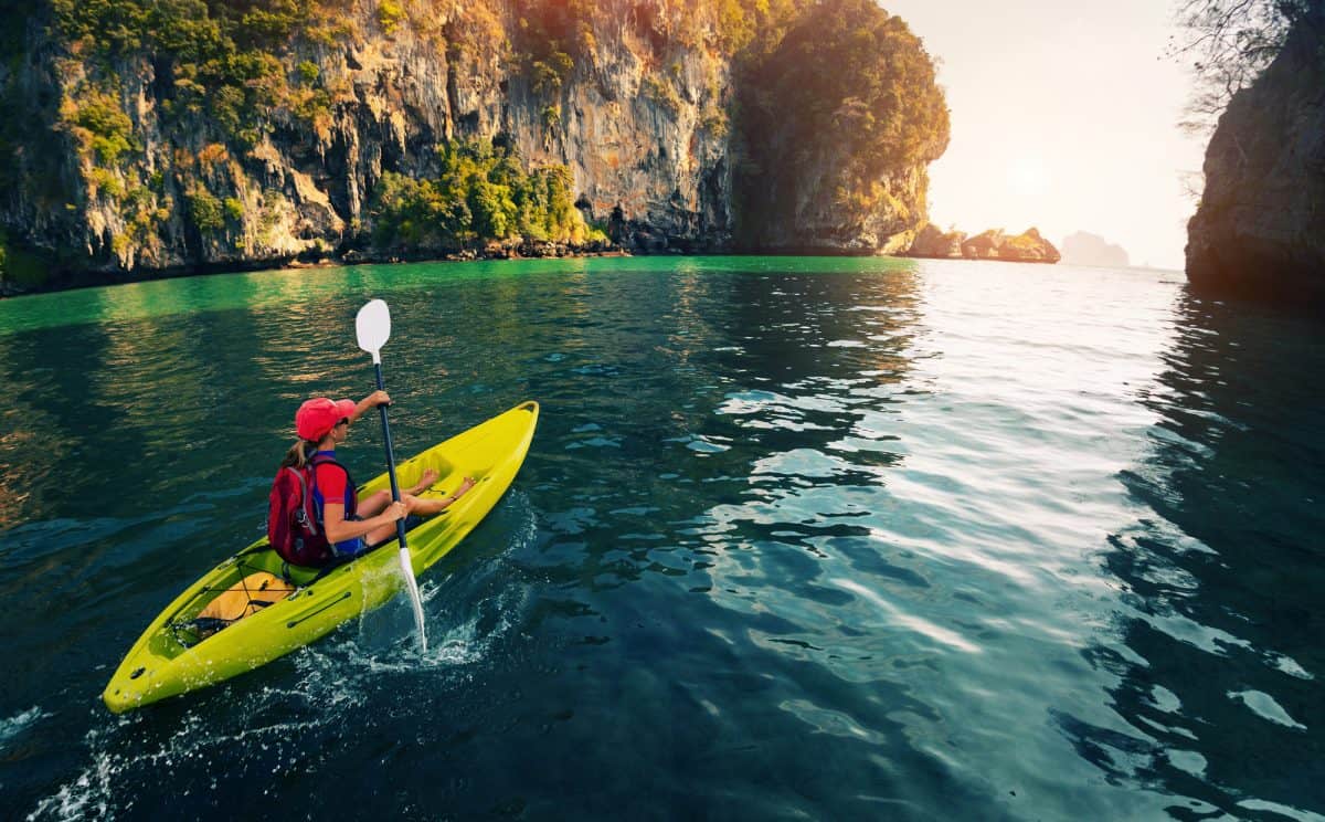 Young lady paddling the Sit-on kayak in the calm bay 